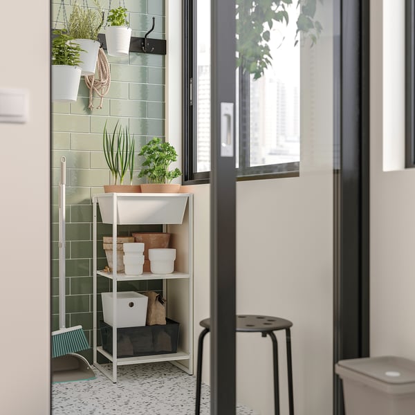 Moderne badkamer met groen betegelde wanden, witte opbergplank met potplanten.