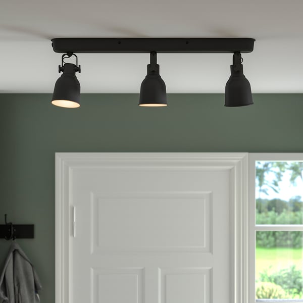 Drie zwarte slimme lampen op een plafondbevestiging geven warm licht uit.