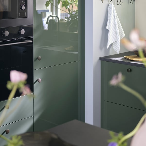 Moderne keuken voorzien van KALLARP groene hoogglans kasten met zwart aanrechtblad en oven.