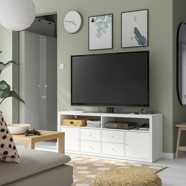 Moderne woonkamer met KALLAX tv-meubel, controllers en bank.