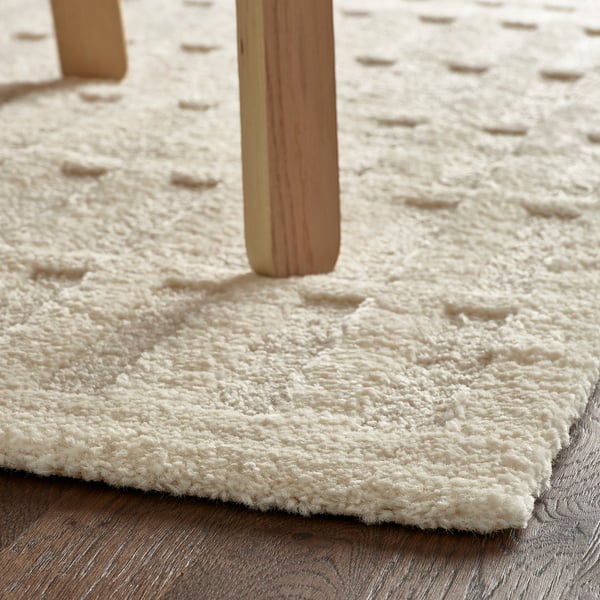 Houten meubelpoten op een getextureerd, ivoorkleurig tapijt