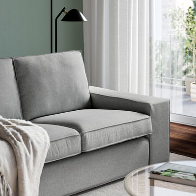 Een comfortabele bank met afneembare armleuningen staat bij een groot raam en biedt een ontspannende plek om te ontspannen.