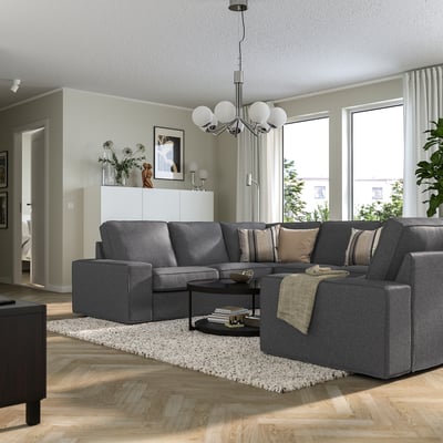 Moderne woonkamer met KIVIK sectionele bank, houten vloeren en grote ramen.