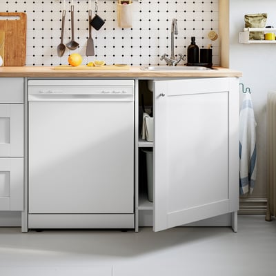 Moderne keuken met witte kasten, houten aanrechtblad, geïntegreerde vaatwasser en spoelbak.