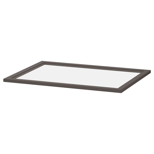 Een donkergrijze KOMPLEMENT glazen plank met een frame van vezelplaat en gehard glas, ontworpen om gemakkelijk te bekijken en op te bergen in een kledingkast.