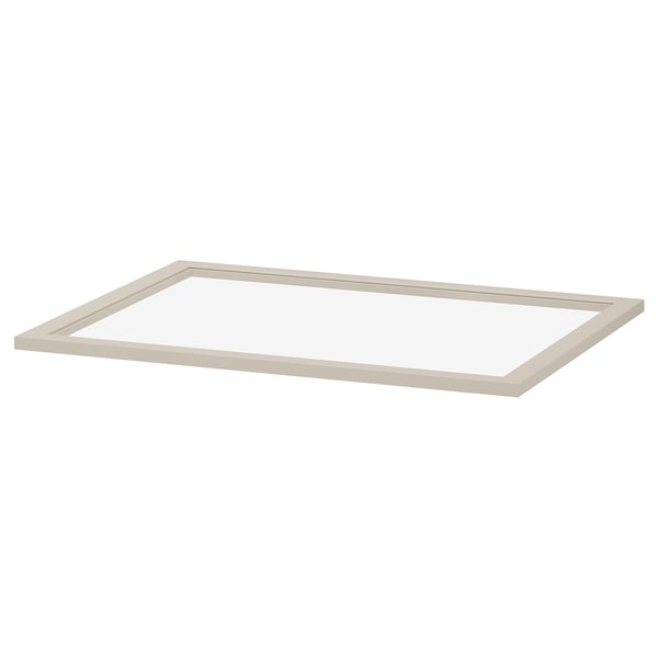 Een KOMPLEMENT glazen plank in beige. Het heeft een rechthoekige vorm met een frame van vezelplaat en een centrum van gehard glas, ontworpen voor het opbergen van kledingkasten.