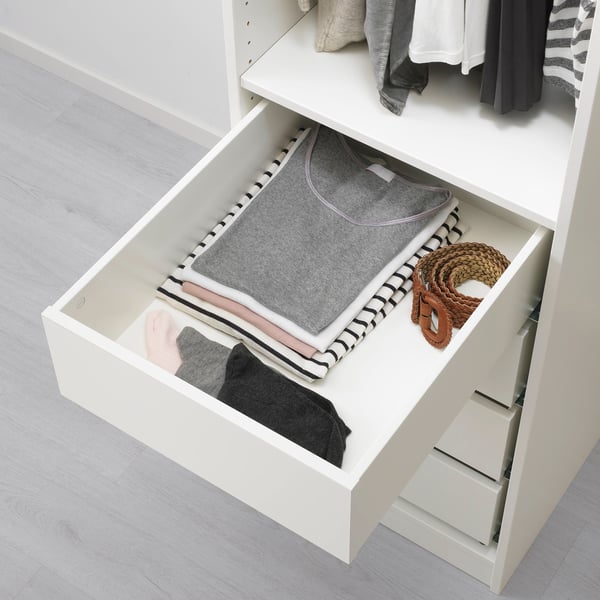 Open lade met opgevouwen kleding, riem en KOMPLEMENT doos voor kleine spullen.