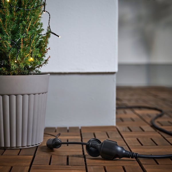 Buitenverlengsnoer verbind met een kerstboom in een pot, zodat er buiten stroom wordt geleverd.
