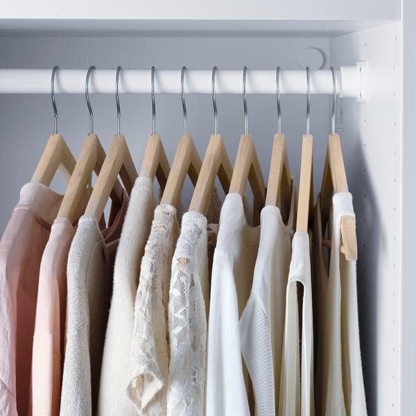 Houten hangers met groeven voor broeken en overhemden in de kast.