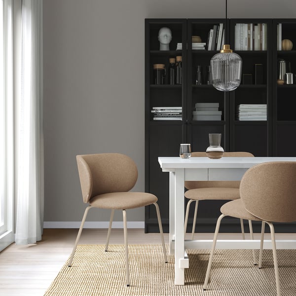 Modern dineren met KRYLBO stoelen rond een witte tafel. Zwarte boekenkast met decor, glazen hanglamp, lichtgrijze muren en lichte houten vloeren.