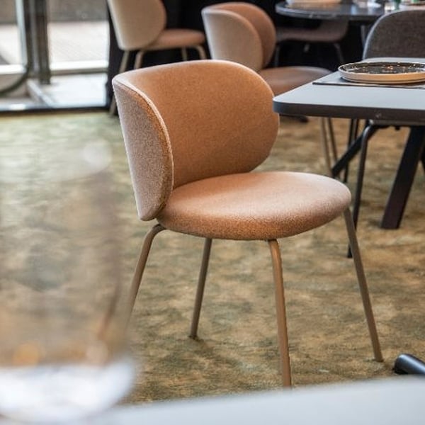 Bruine gestoffeerde eetkamerstoel met metalen poten en een gebogen rugleuning, ontworpen voor comfort tijdens lange maaltijden.