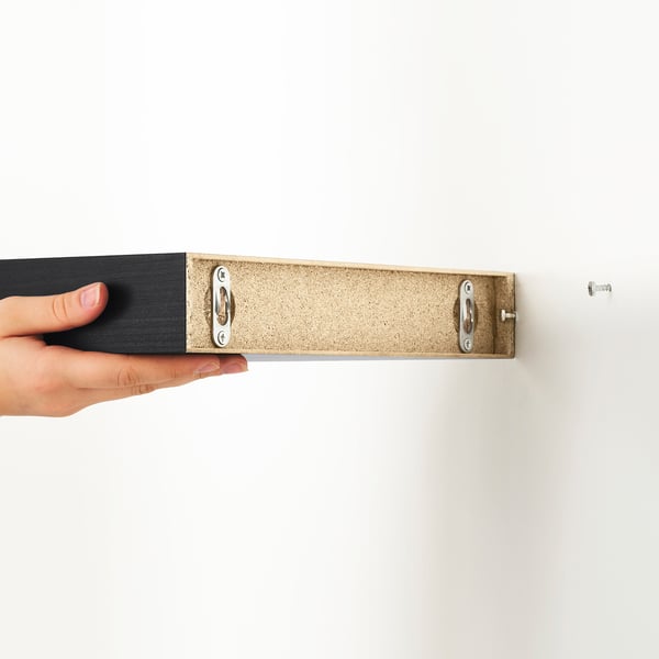 Hand met slanke houten wandplank met verborgen bevestigingen.