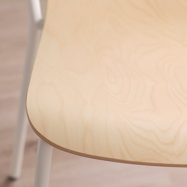 Close-up van een stevig, licht berkenfineer tafelblad met zichtbare houtnerf, ondersteund door witte metalen poten.