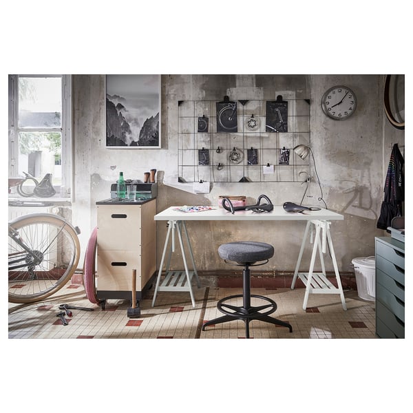 Werkruimte met een industrieel thema met witte LAGKAPTEN-tafel, zwarte kruk en diverse decoratieve artikelen.