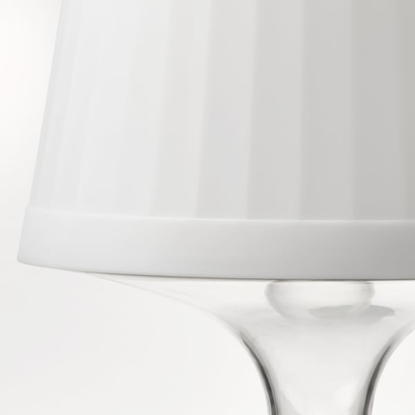 Afbeelding toont een strakke, moderne lamp met een witte kap en een heldere voet van polycarbonaat. Goed ontworpen, draagbaar en veelzijdig.