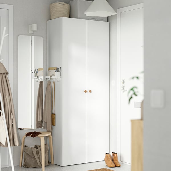 LASTARE garderobe tussen spiegel en muur. Smalle, verticale opslag met deuren, manden en lamp.