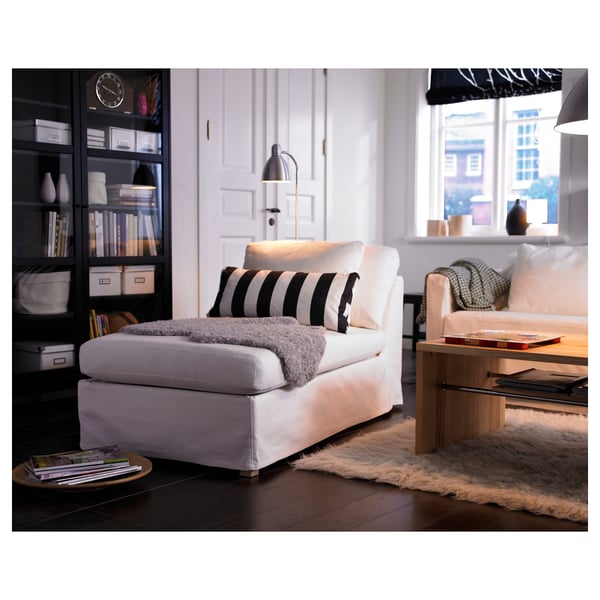 Moderne woonkamer met een witte LERSTA vloerlamp met een zwart-wit gestreepte stoel, een houten salontafel, een gezellig vloerkleed en een boekenplank.