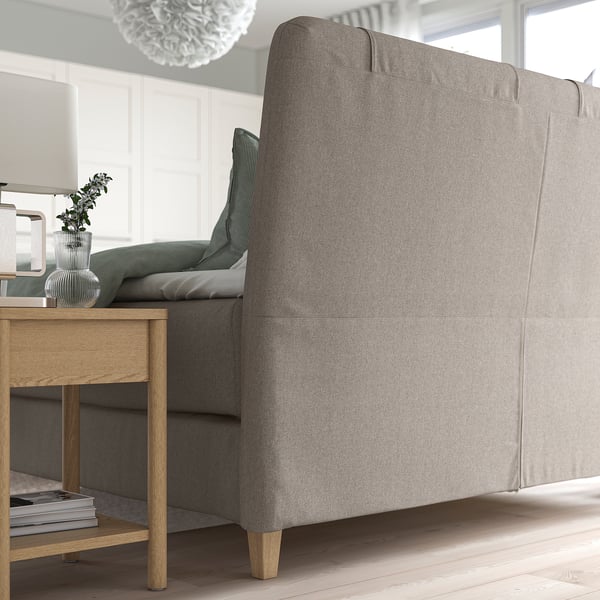 Modern bed met hoofdeinde met kussens, houten poten en gezellige kussens.
