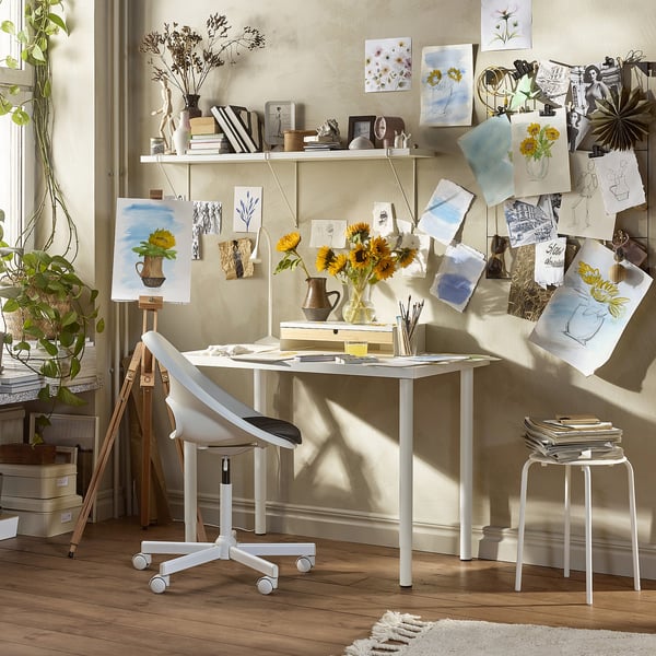 Kunststudio met tafel, stoel, schetsen en zonnebloemen.