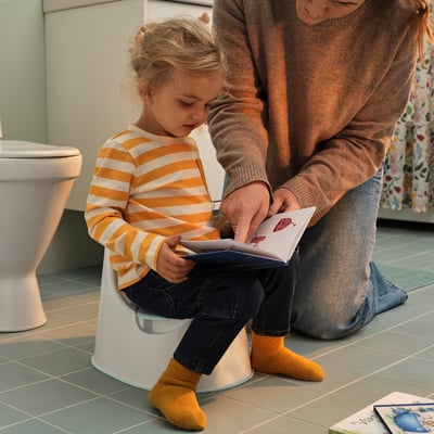 Het meisje leert toilet met hulp van volwassenen te gebruiken.