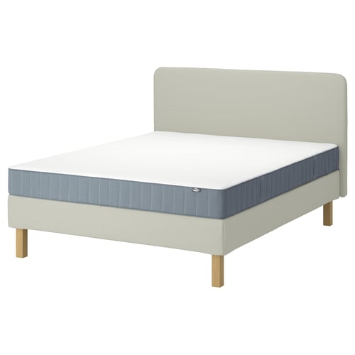 Een beige LYNGÖR-bed met een wit en blauw matras. Het bed heeft een gevoerd hoofdeinde en houten poten.