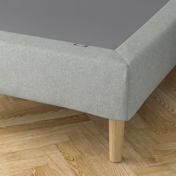 Modern bed met lichtgrijs gestoffeerde onderstel, houten poten en een donkergrijs matras. Gemaakt met kwaliteitsmaterialen.