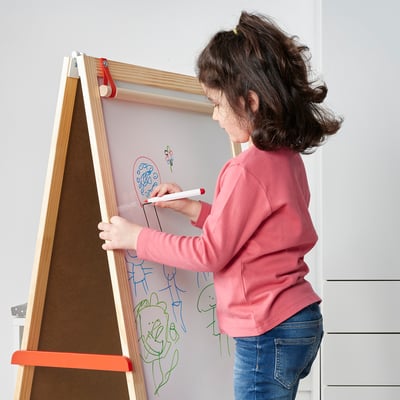 Kind tekening op een whiteboard met een stift. Het bord heeft een markerhouder en is bevestigd aan een standaard.