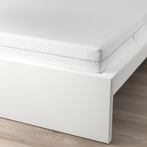 Een wit MALM bedframe met een hoog hoofdeinde, ontworpen om comfortabel te zitten. De verstelbare bedzijden zijn geschikt voor verschillende matrasdiktes.