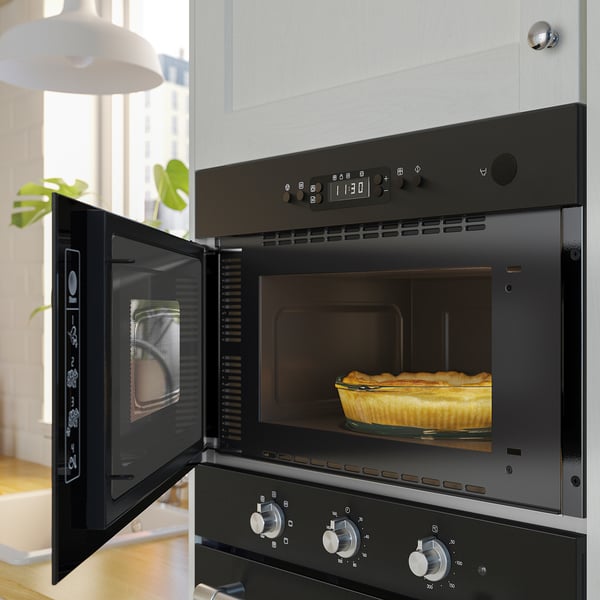 Zwarte inbouw magnetron met roestvrijstalen knoppen, waardoor er een goudbruine quiche van binnen ontstaat.