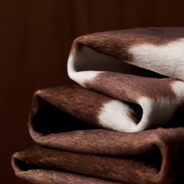Koeienhuidpatroon netjes opgevouwen. Zacht, duurzaam polyester materiaal zichtbaar, ideaal voor moderne of rustieke omgevingen.