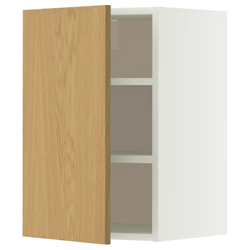 Een open witte METOD wandkast met een licht eikenhouten deur, met daarin twee legplanken.