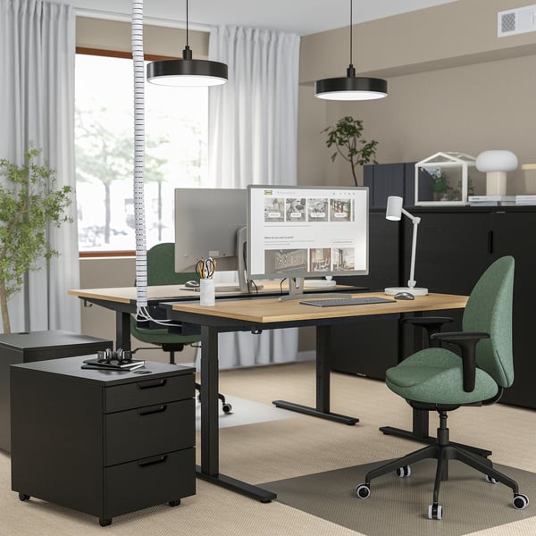 Moderne zwarte kantooropstelling: MITTZON in hoogte verstelbaar bureau met groene stoel, monitor en planten.