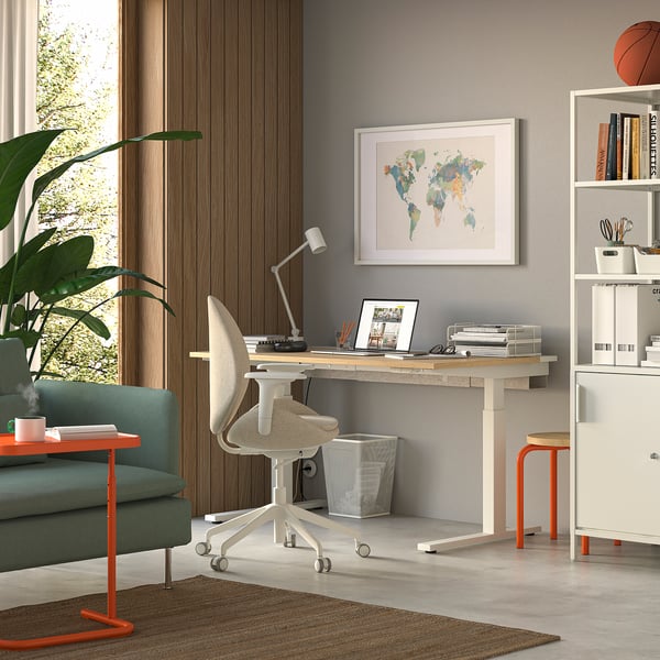 Thuiskantoor: wit bureau, stoel, boekenplanken, wereldkaart, laptop, groene bank, oranje bijzettafel, plant.