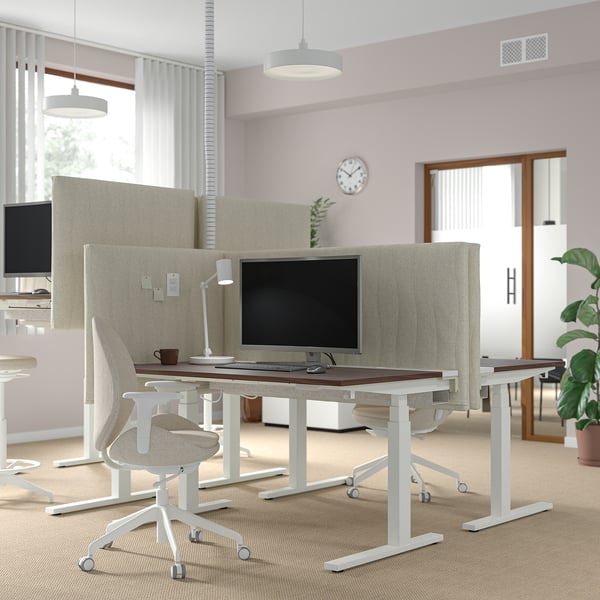 MITTZON zit-sta bureaus in kantoor met hoge schermen, computers en ergonomische stoelen bij ramen.