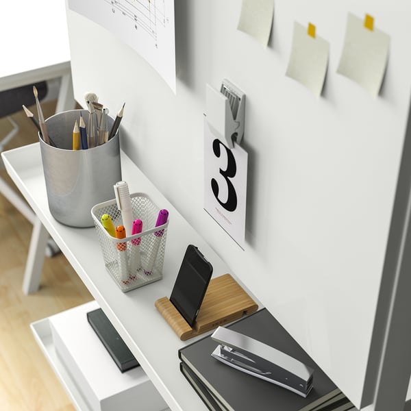 Bureau met whiteboard, pinnen en opbergruimte voor kantoorgereedschap.