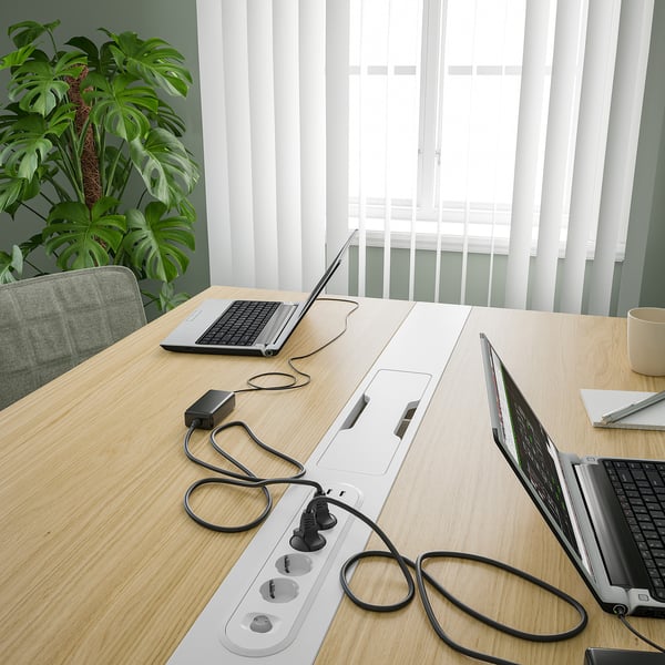 Vergadertafel met laptops en stopcontacten, geschikt voor vergaderingen en werk.