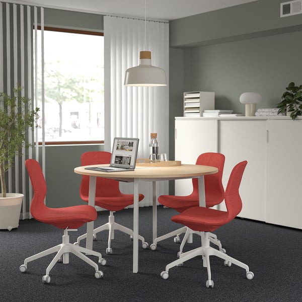 Moderne MITTZON vergadertafel met rode stoelen, houten blad, witte poten, plafondlamp en raam.