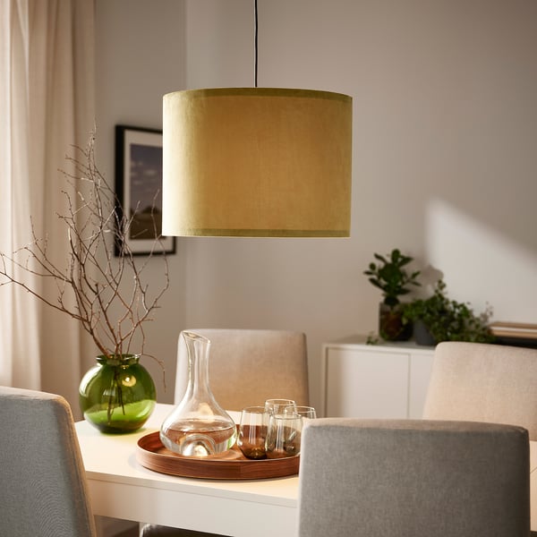 Groene lampenkap over tafel met karaf, vaas, stoelen. Zachte, warme textuur.