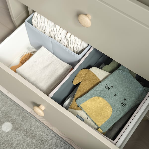 Open lade onthult georganiseerde babykleding en accessoires.