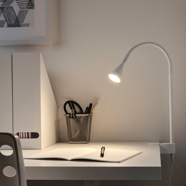 Zilveren NÄVLINGE lamp geklemd op bureau met pennenhouder en boek.