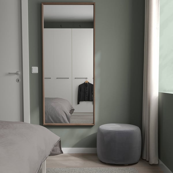 Minimalistische slaapkamer met NISSEDAL spiegel, bed, poef, gedempte groene muren, kast.