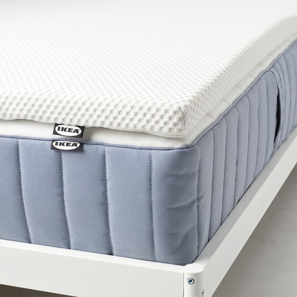 IKEA NORDBERGET traagschuim matrasbeschermer op bed, witte hoes, zacht en drukverlagend.