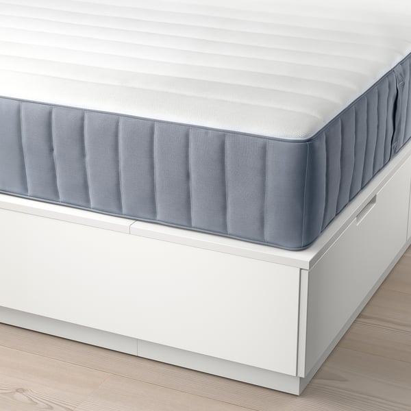 Een knus NORDLI bed met een comfortabele matras op drie ladeblokken, ideaal voor compacte ruimtes.