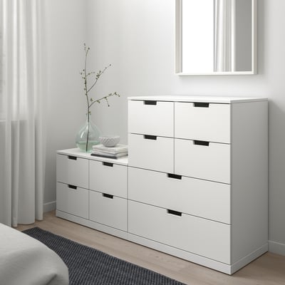 NORDLI ladekast met 6 lades in de slaapkamer, modern wit, donkere handgrepen, bij bed met spiegel en vaas.