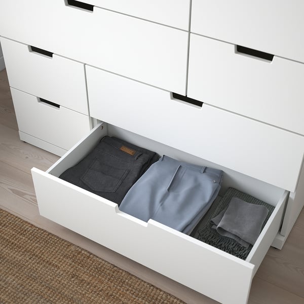 Open witte lade met opgevouwen jeans en overhemden, onderdeel van de NORDLI modulaire kist.