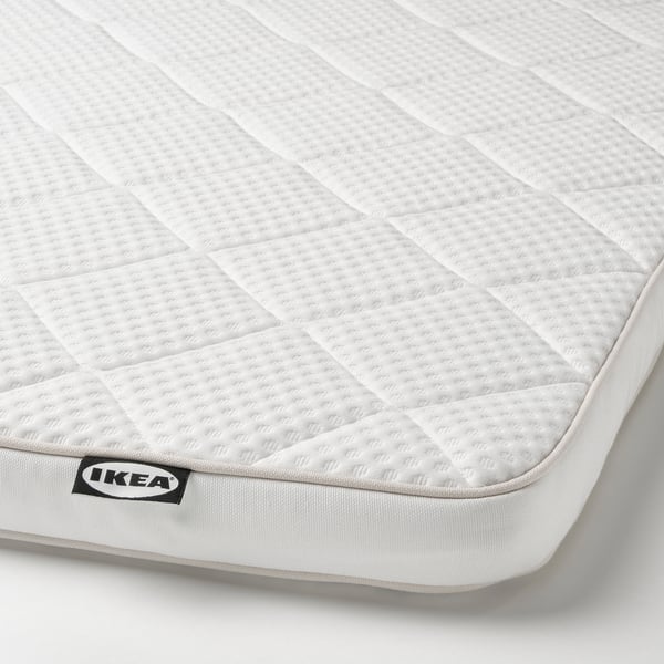 Close-up van een witte IKEA-matrasbeschermer met een ruitpatroon. De gedetailleerde stiksels en het hoogwaardige materiaal, met de nadruk op comfort en ondersteuning.