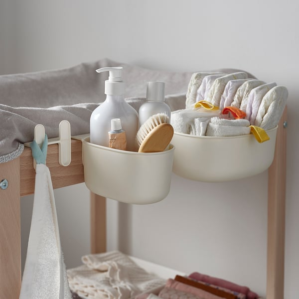 Commode met hangende manden: men houdt zeep, lotion, borstel vast; andere bevat opgevouwen handdoeken met linten. Haken houden een handdoek en doek vast.