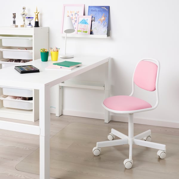 Kinderbureaustoel met zwenkwielen, verstelbare zitting, onder georganiseerd bureau met schoolspullen. Planken daarachter bevatten trofeeën, kunst.
