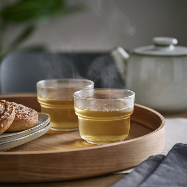 Twee glazen thee op houten dienblad, stomen, met een theepot.
