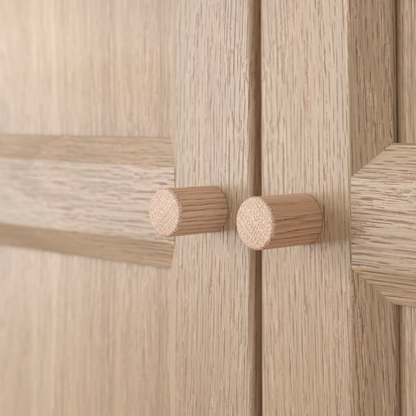 Houten kastknoppen: twee ronde, natuurlijke houten knoppen op een lichthouten deur, met een kwaliteitsontwerp.